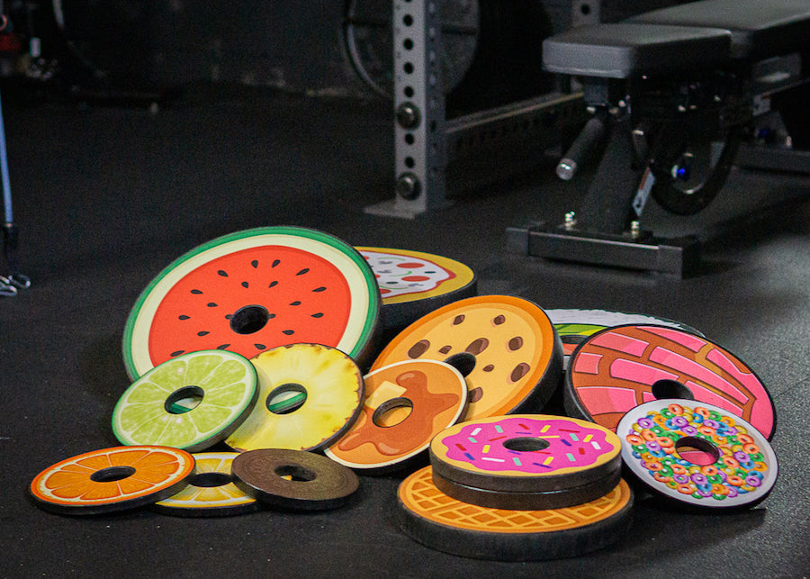 Weight plates coved with various Plate Snacks designs piled up on gym floor