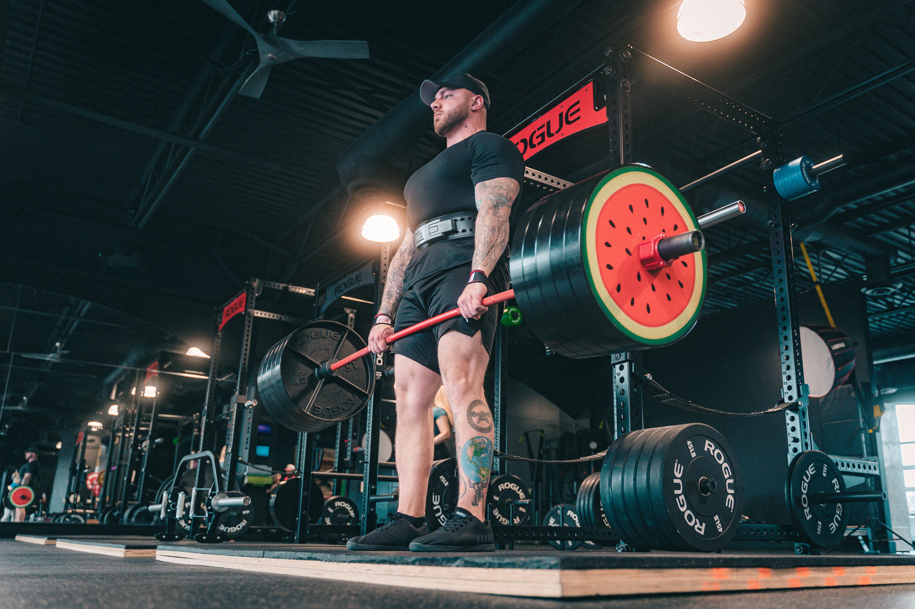 Man deadlifting barbell with watermelon weight plates on it